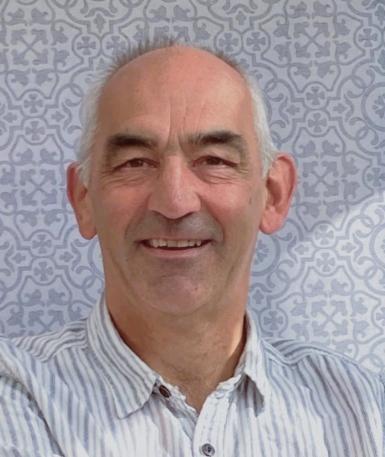 A man looking at the camera wearing a white and grey striped shirt.