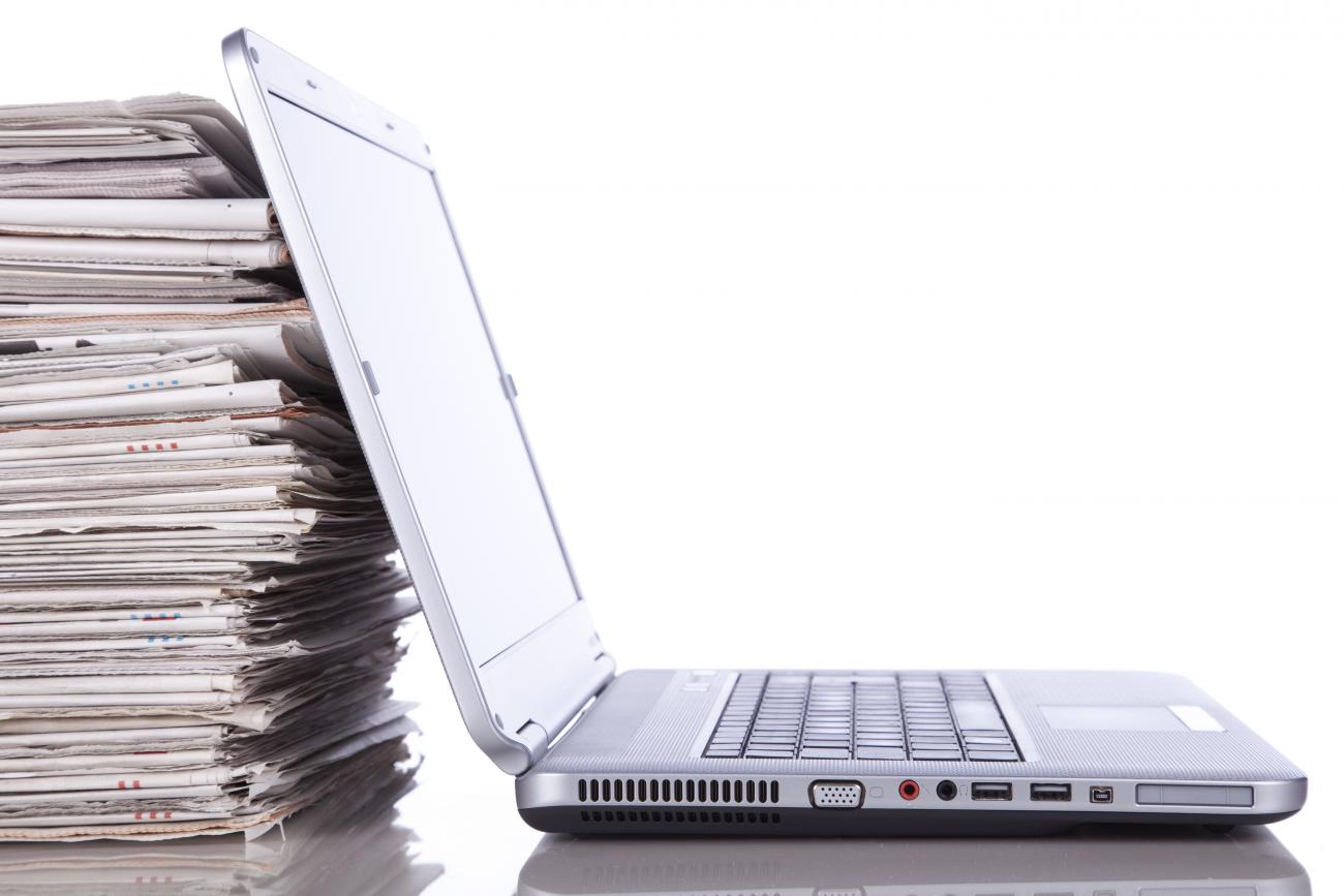 Laptop next to pile of papers. Thumbnail