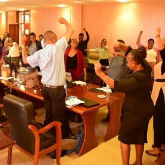 People stood around a desk with their arms in the air celebrating